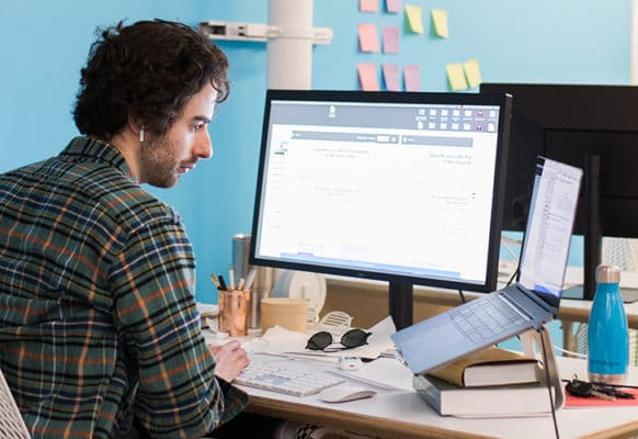 layout by flywheel design perfect website navigation man sitting and designing at desk near blue wall and sticky notes