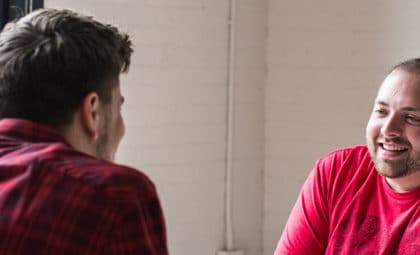 layout by flywheel sell clients on new content management platform from business catalyst two men talking near bright window and white brick wall