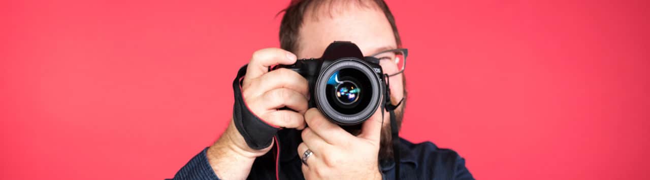 layout by flywheel use images on website get sales conversions man taking photo with DSLR camera on red background