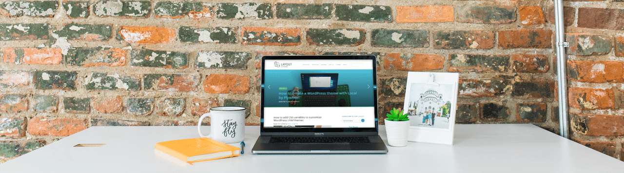 inspiring wordpress website designs blog on laptop with desk scene on brick wall
