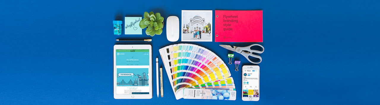 how to create a consistent brand across marketing channels example layout with branding and office supplies with flywheel branding website and instagram @heyflywheel on technology