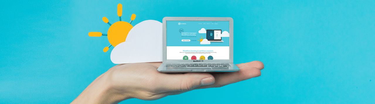 laptop with paper clounds sitting on hand with flywheel cloud hosting website on screen
