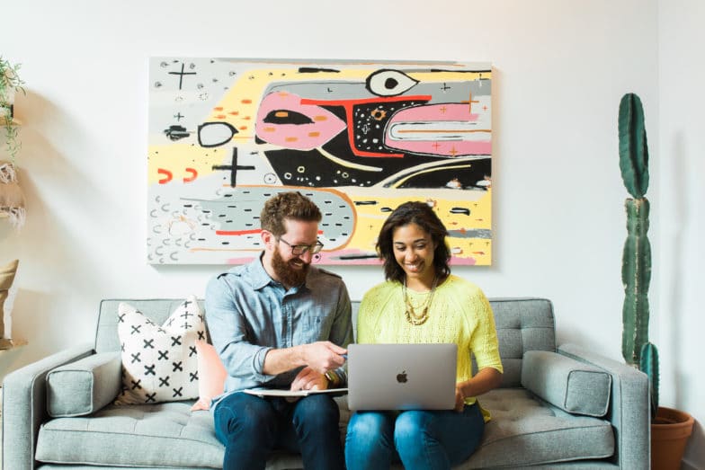 two developers smile at a laptop screen as they review their design