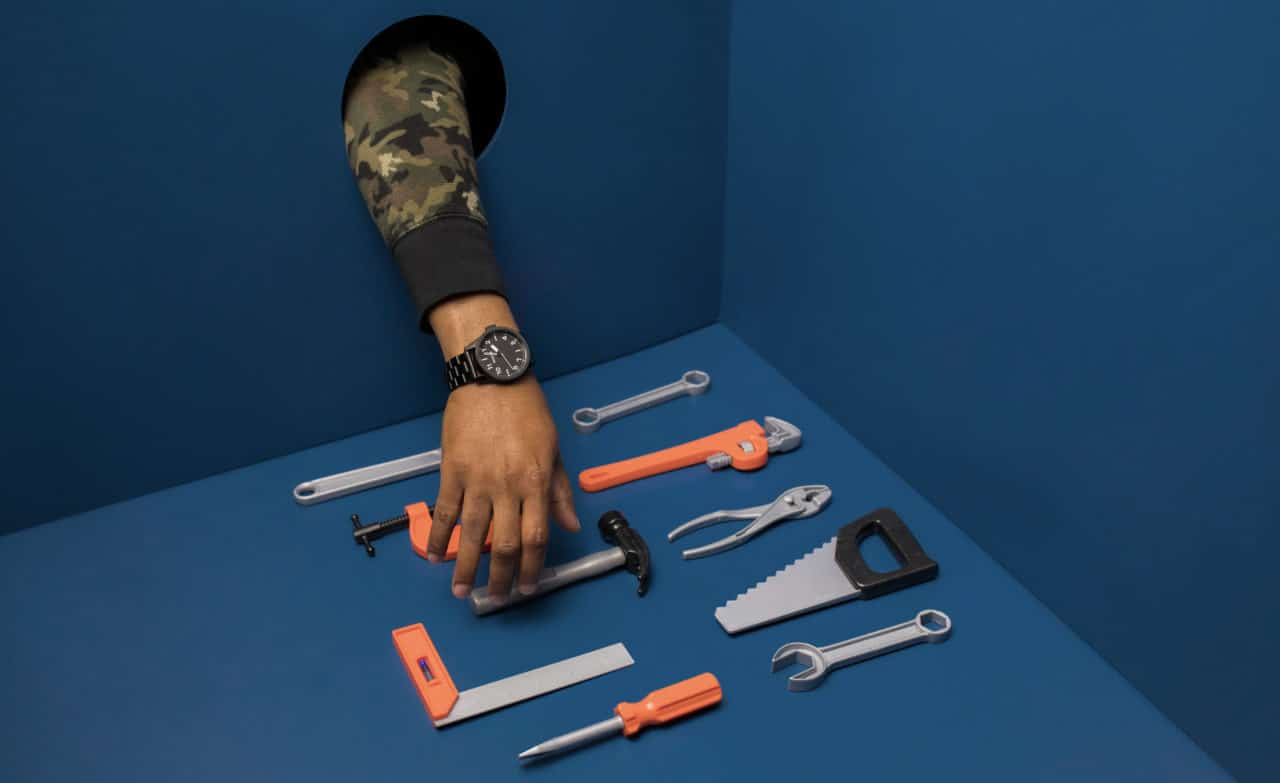 a hand chooses from an array of tools, including a wrench, a saw, a screwdriver, and a hammer