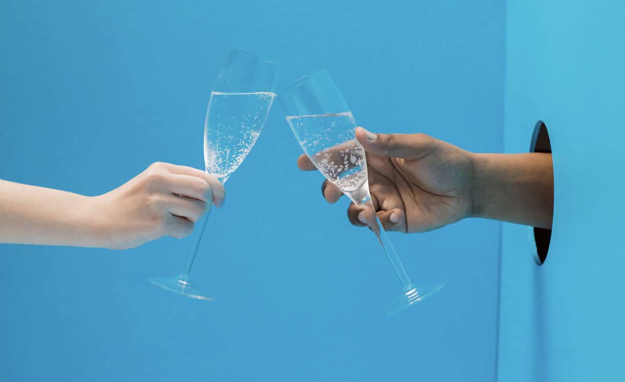 two hands clink champagne flutes