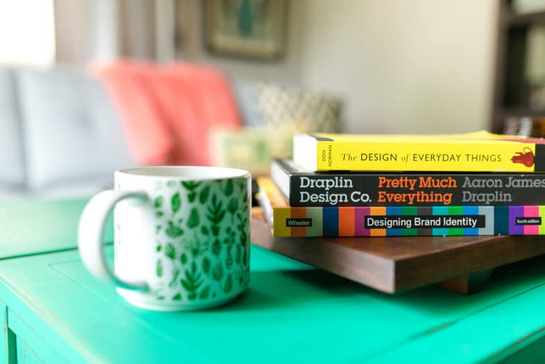 Books about design on a table and a mug.