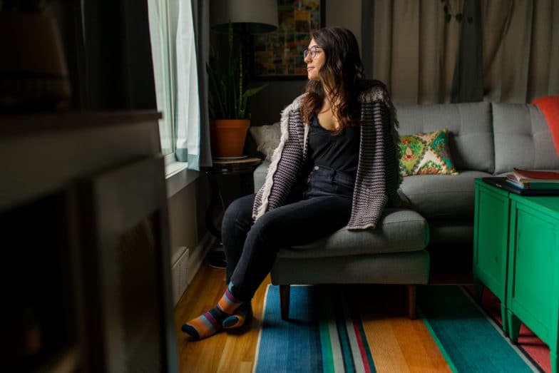 Woman sitting on her couch looking out the window. 