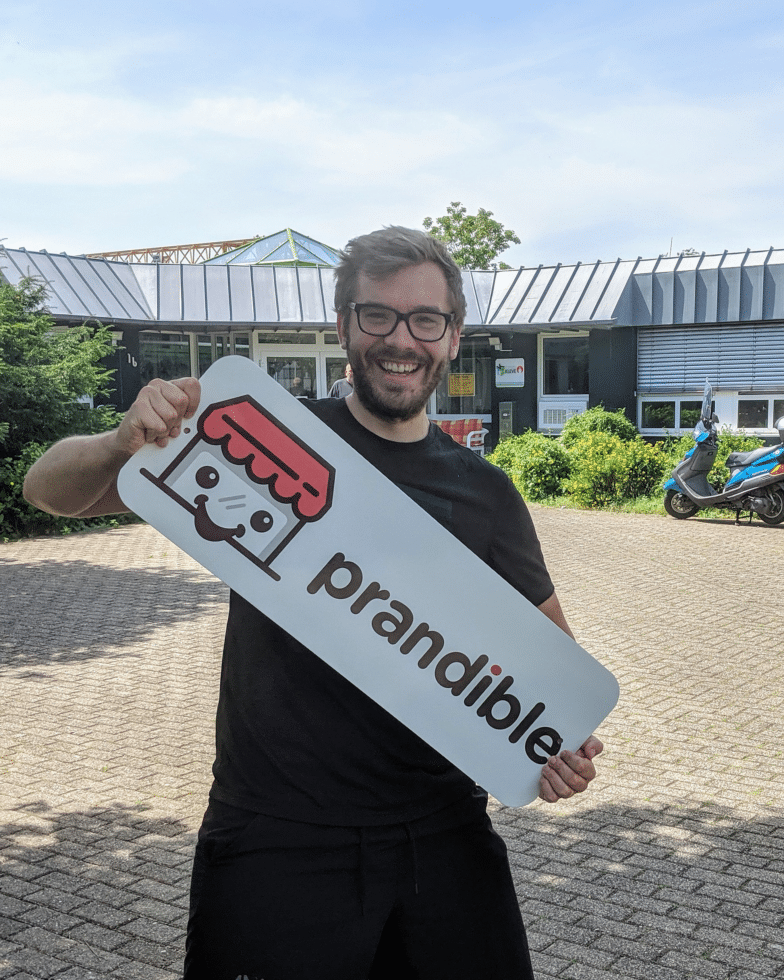 Man holds sign displaying Prandible logo