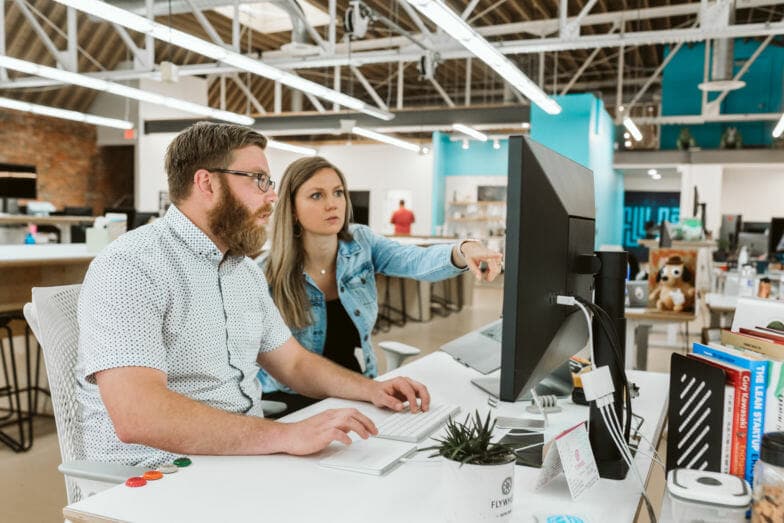 Two employees looking at computer screens in an office 