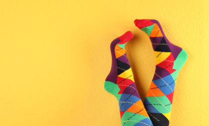feet wearing colorful argyle socks on a yellow background