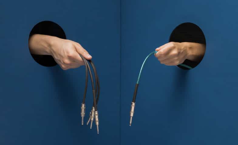 two hands hold cords with plugins at the ends