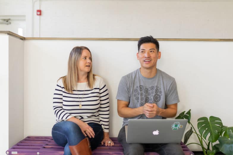 two people discuss a project while sitting on a purple bench