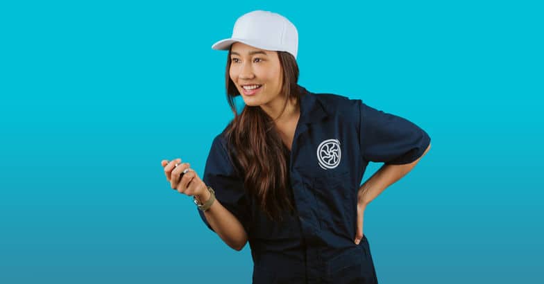 a woman in a white hat stands in front of a blue backdrop 