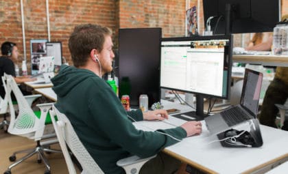 man working at a desk on a desktop computer