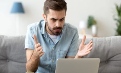 man sitting at computer looking frustrated