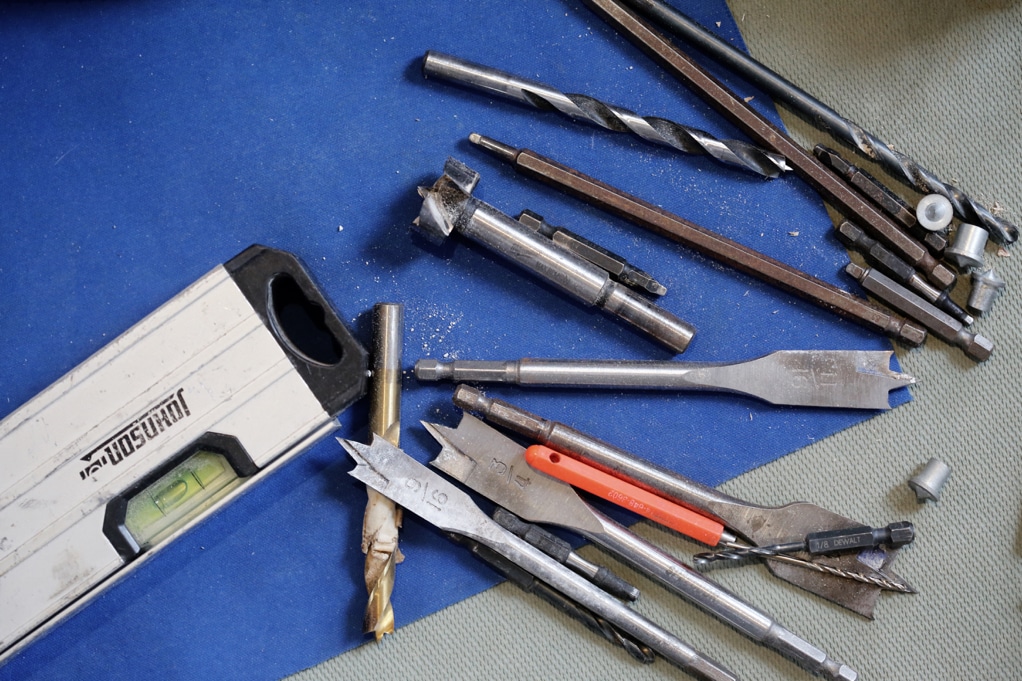 various tools and drill bits as well as a level on a blue background