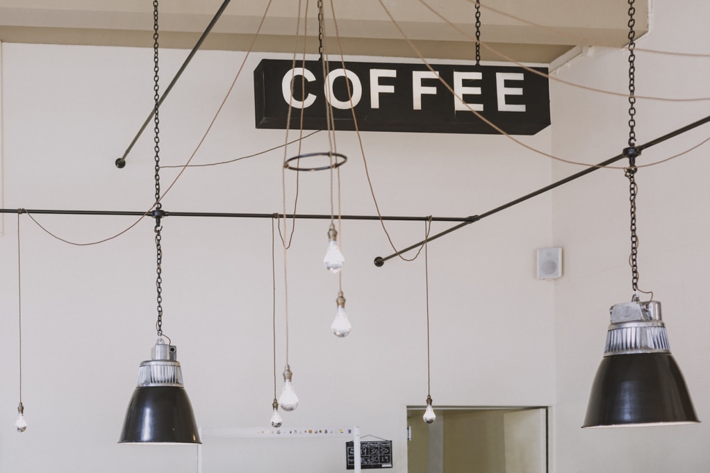 Ceiling of a coffee shop with lamp lights and a large sign that read "Coffee"