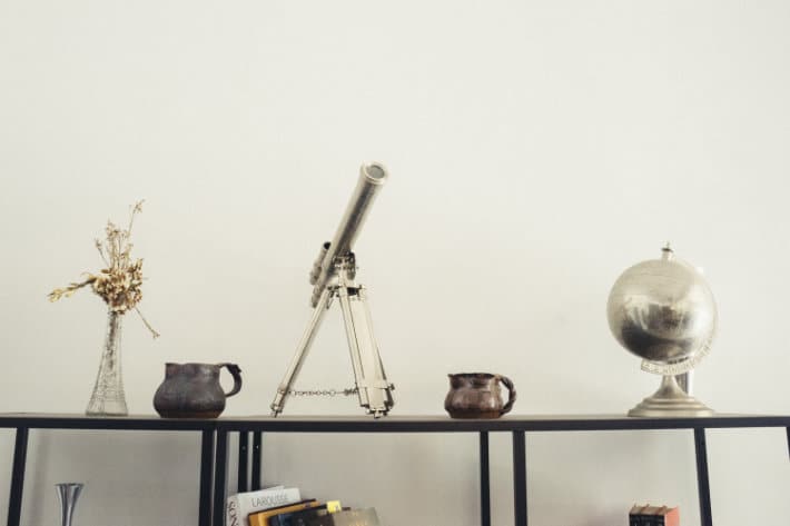 a telescope, a globe, and other trinkets sit atop a table