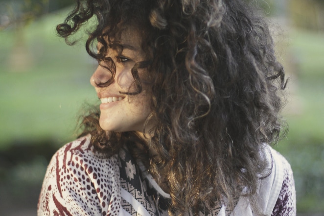 Portrait shot of a woman's profile. She's smiling and has curly brown hair