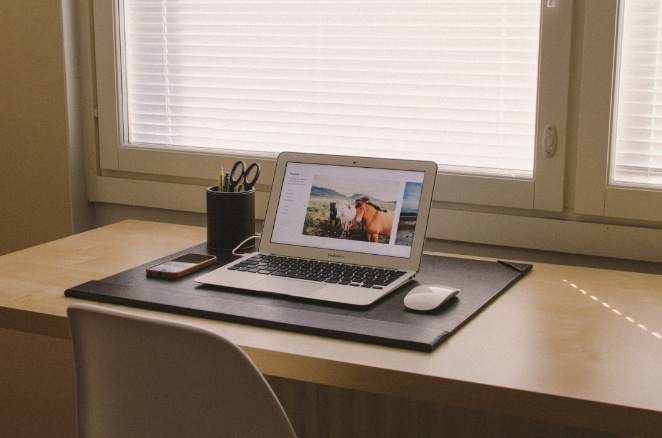 a neat desk with a utensil holder, phone, laptop, and mouse