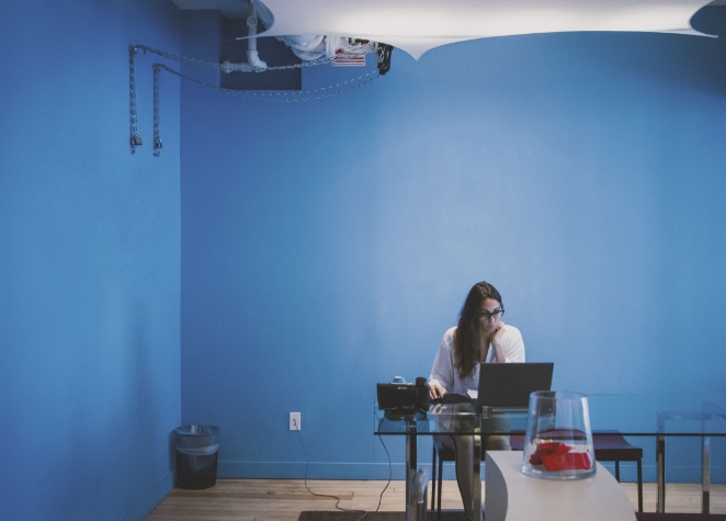 a woman works at a computer in a blue room