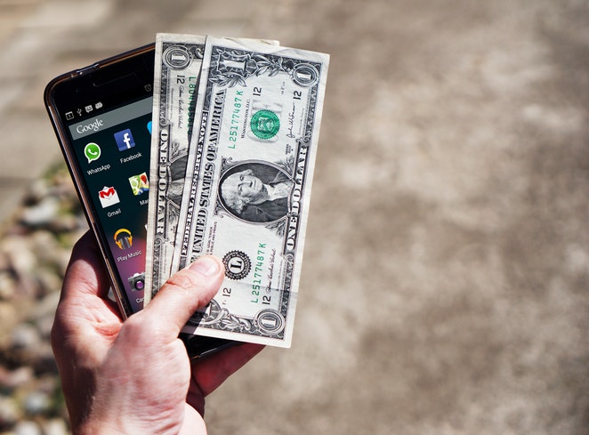 mobile phone and two dollar bills in hand