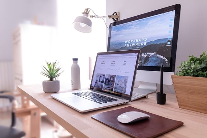 layout by flywheel invest money freelance business laptop desk top and phone sitting on desk with plants and lamp in background
