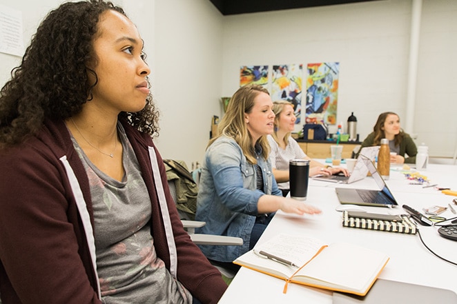 layout by flywheel develop marketing strategy for design agency how to women sitting at table with notebooks and laptops in brainstorm