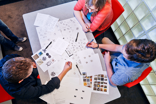 team of three working at a table with design sketches outlined