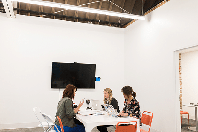 three flywheel women discussing objectives for successful user testing in large open white coworking space