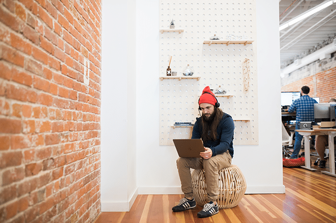 man on laptop next to plant wall with bricks using facebook advertising tools to increase sales
