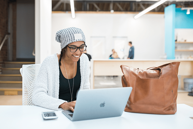 woman working on laptop in large white space with bag nearby learning lessons design classes won't teach you