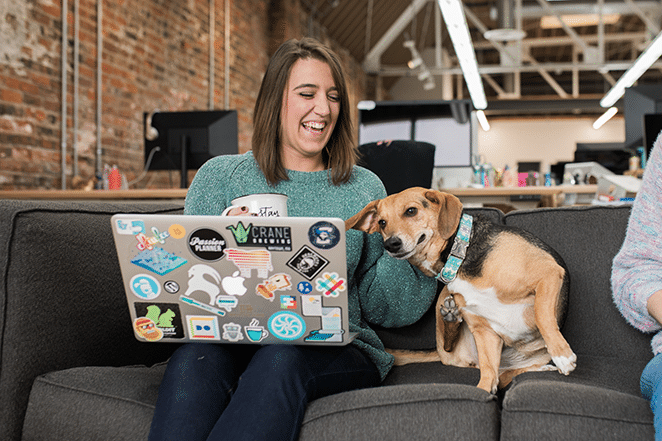 woman and dog on couch with coffee and laptop measuring content metrics